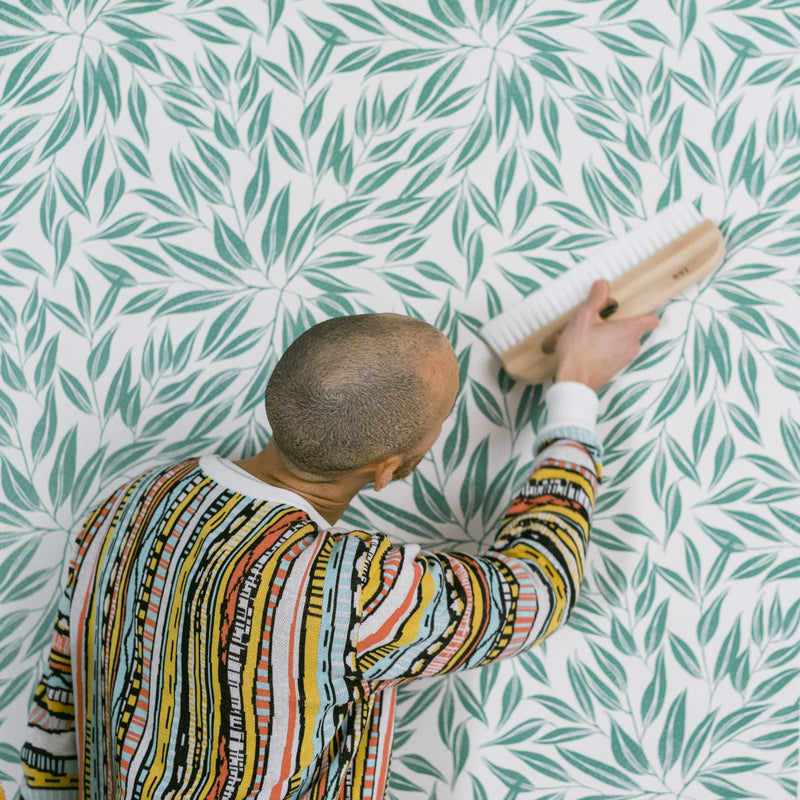Man smoothing Lick Botanical 03 Wallpaper onto a wall