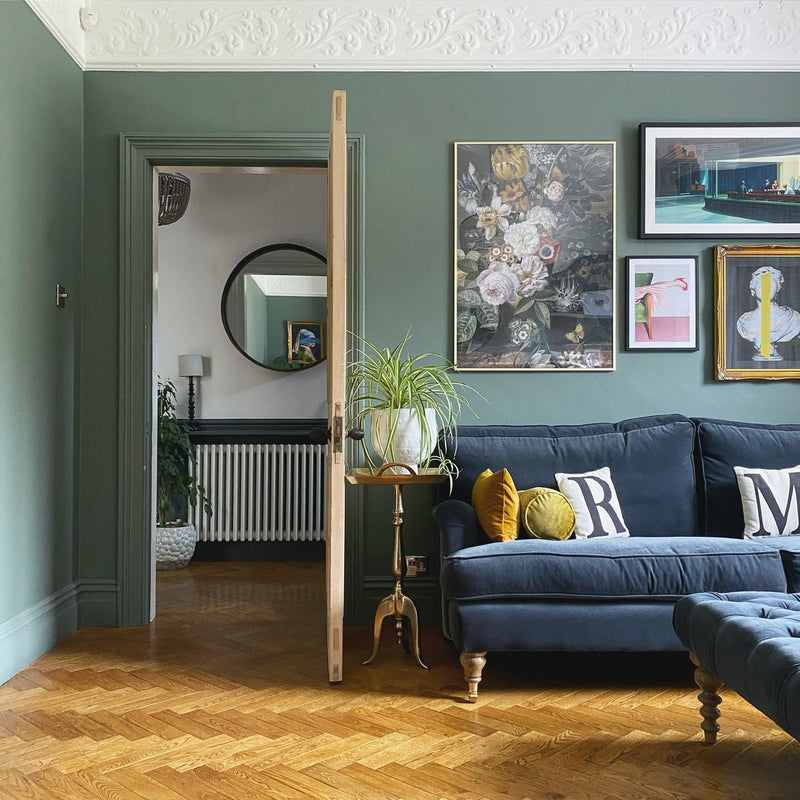 Green living room walls with blue velvet sofa 