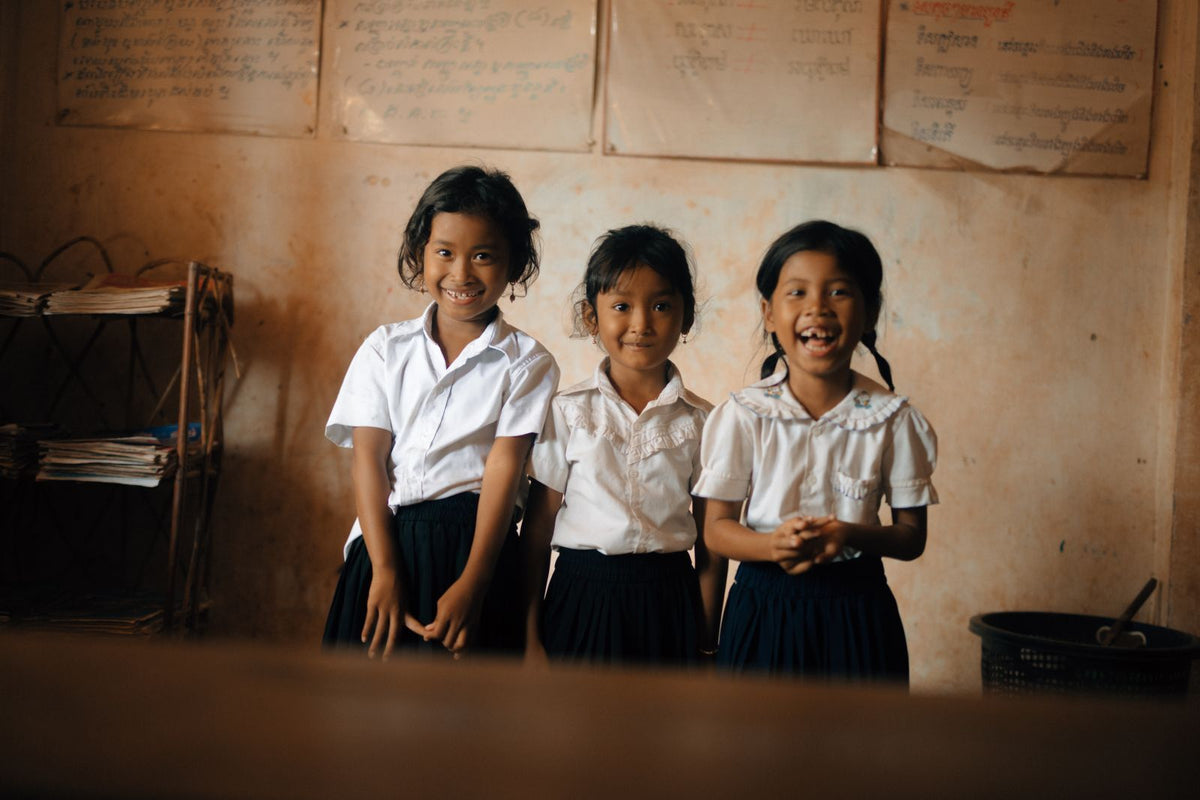 A group of girls in school uniform smiling for charity: water